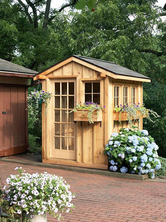 a garden shed with flowers in the front