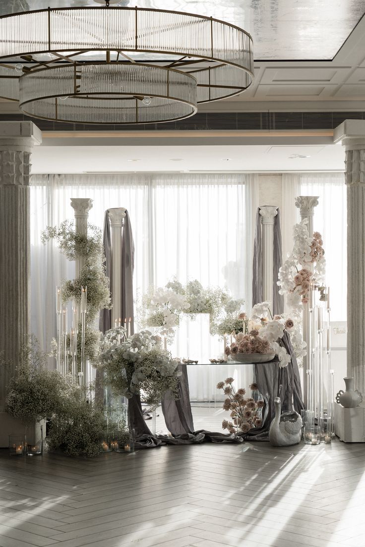 the room is decorated with flowers and vases on the table in front of large windows