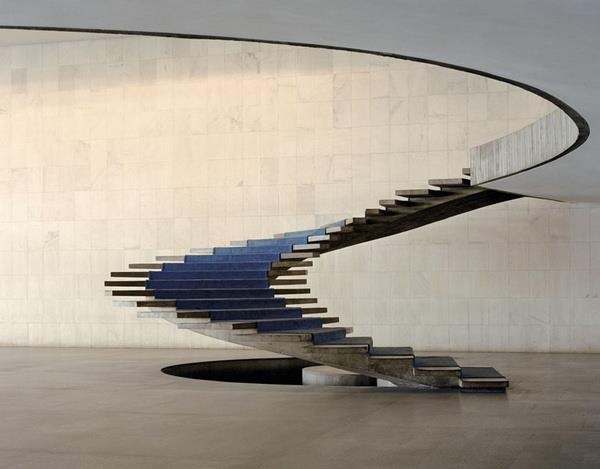 a spiral staircase made out of metal and blue chairs