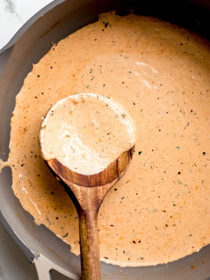 a wooden spoon in a pot filled with sauce