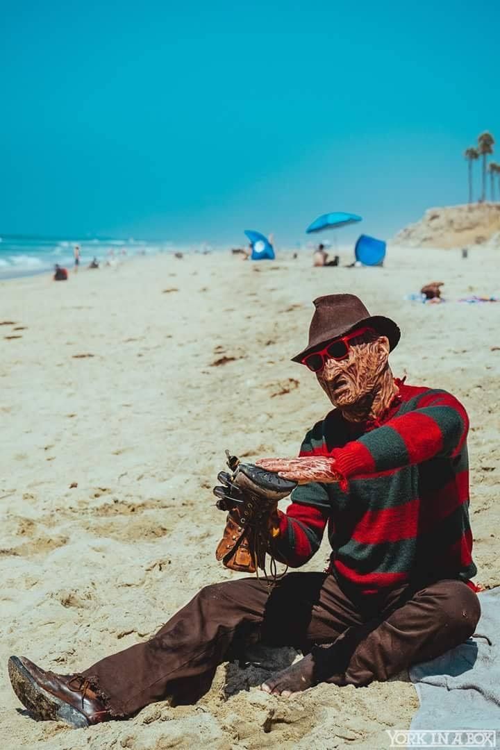 a man sitting on top of a sandy beach next to the ocean holding a glove