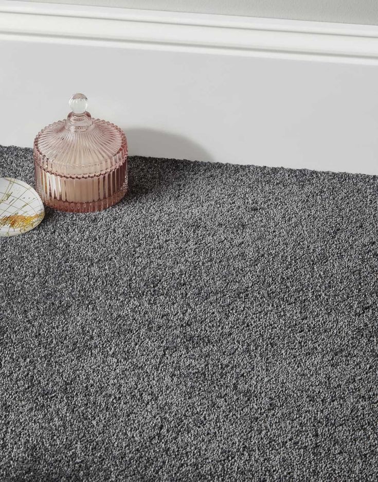 a grey carpet with a pink vase next to it