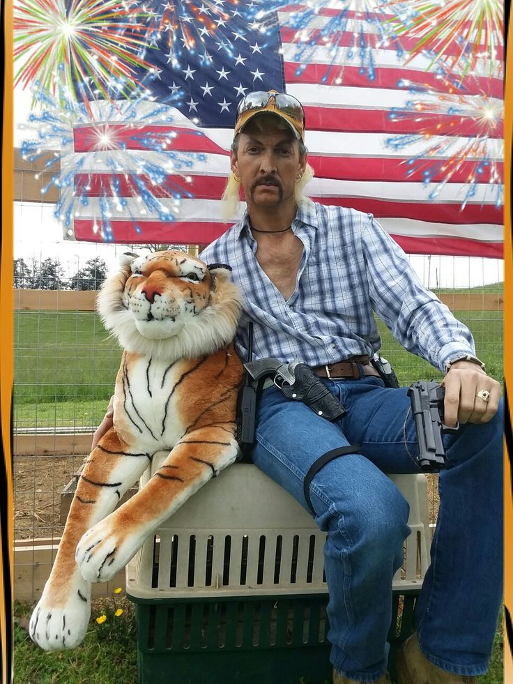 a man sitting on top of a chair next to a large stuffed tiger in front of an american flag