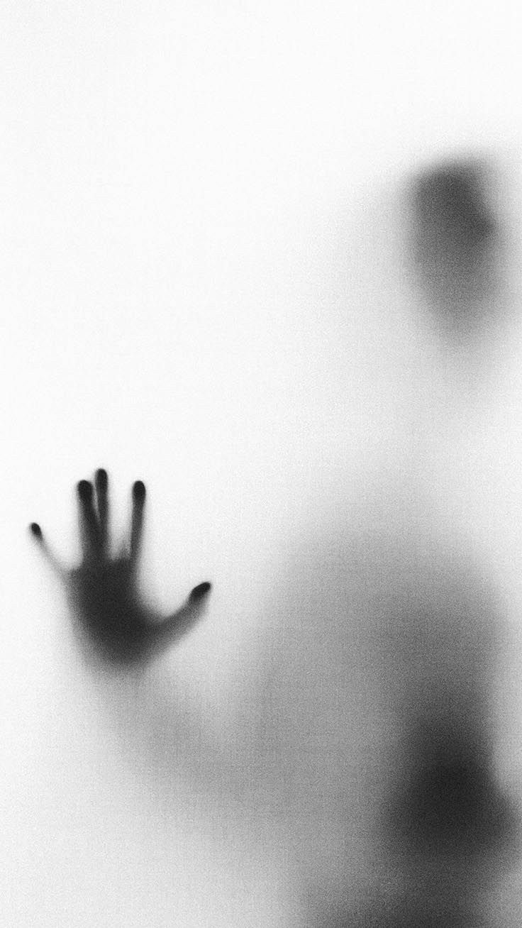 a blurry image of a person's hand reaching out from behind a wall