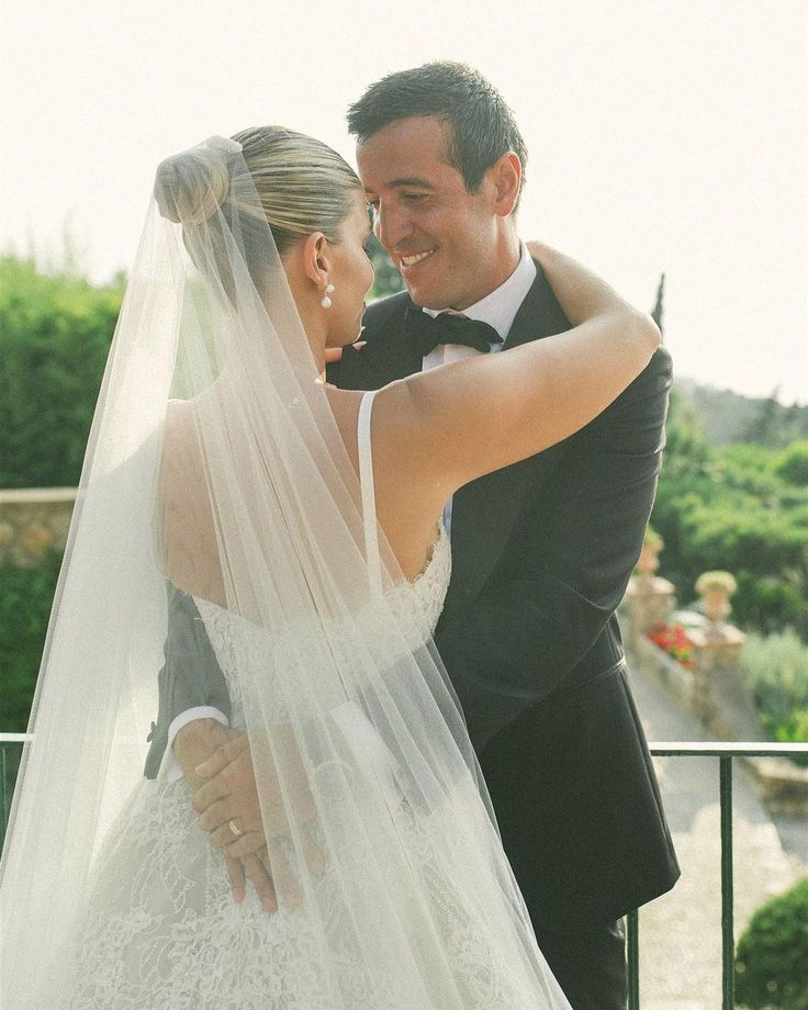 a bride and groom embracing each other in front of a balcony with greenery on either side