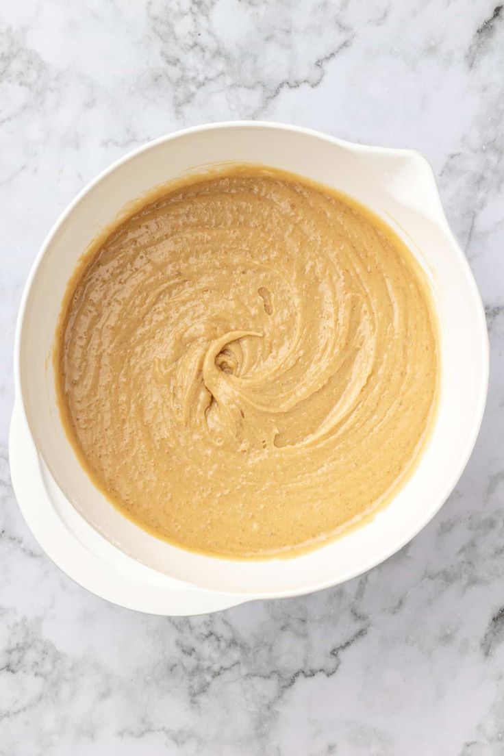 a white bowl filled with peanut butter on top of a marble counter