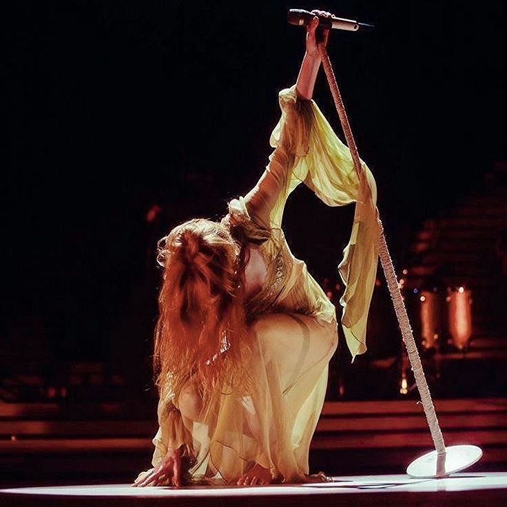 a woman is performing on stage with a pole