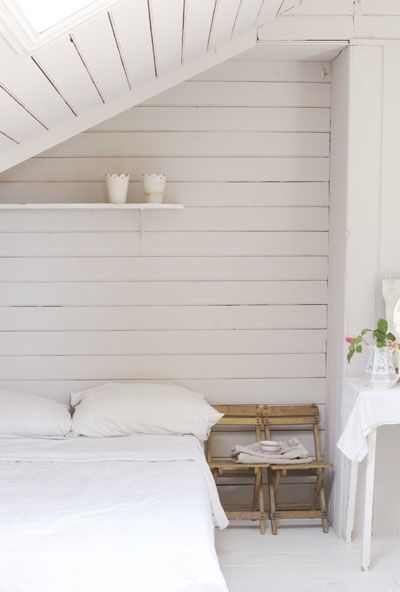 a bed sitting under a white roof next to a table and chair in a room