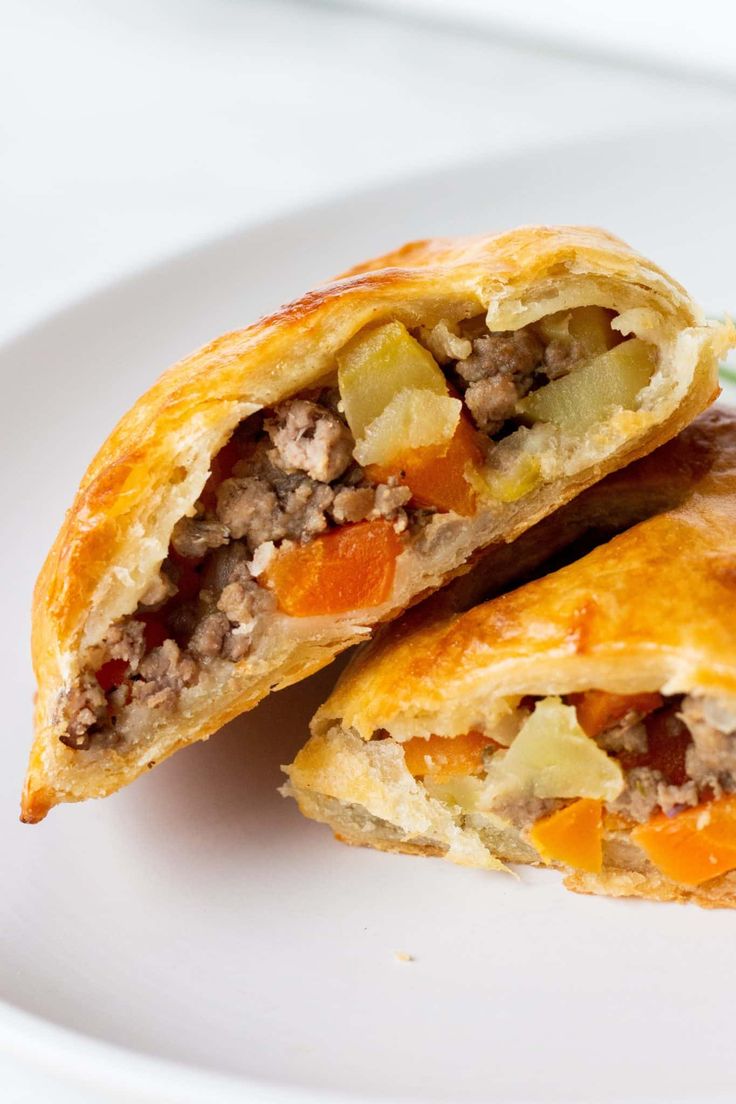 two pastries on a white plate, one with meat and vegetables