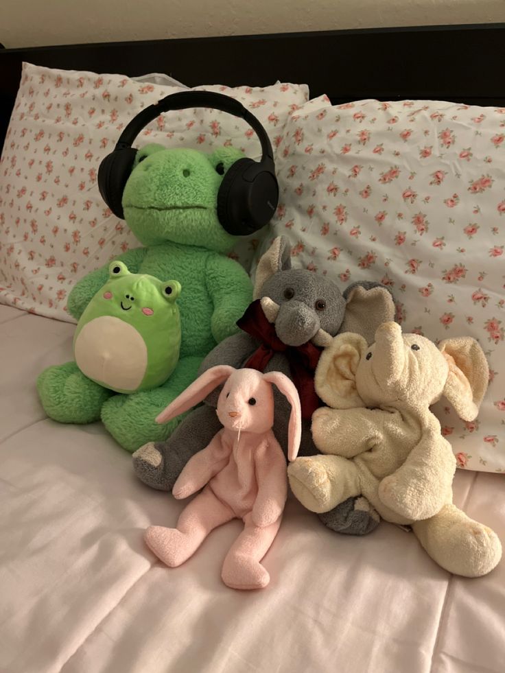 several stuffed animals on a bed with headphones