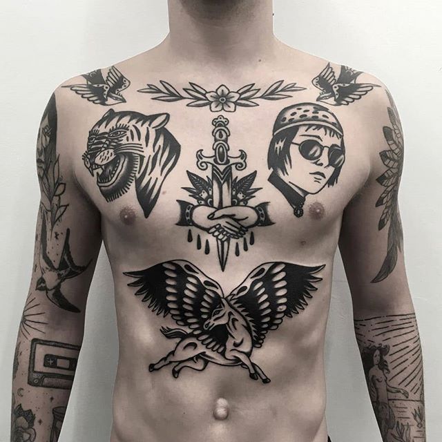 a man with many tattoos on his body and chest is standing in front of a white wall