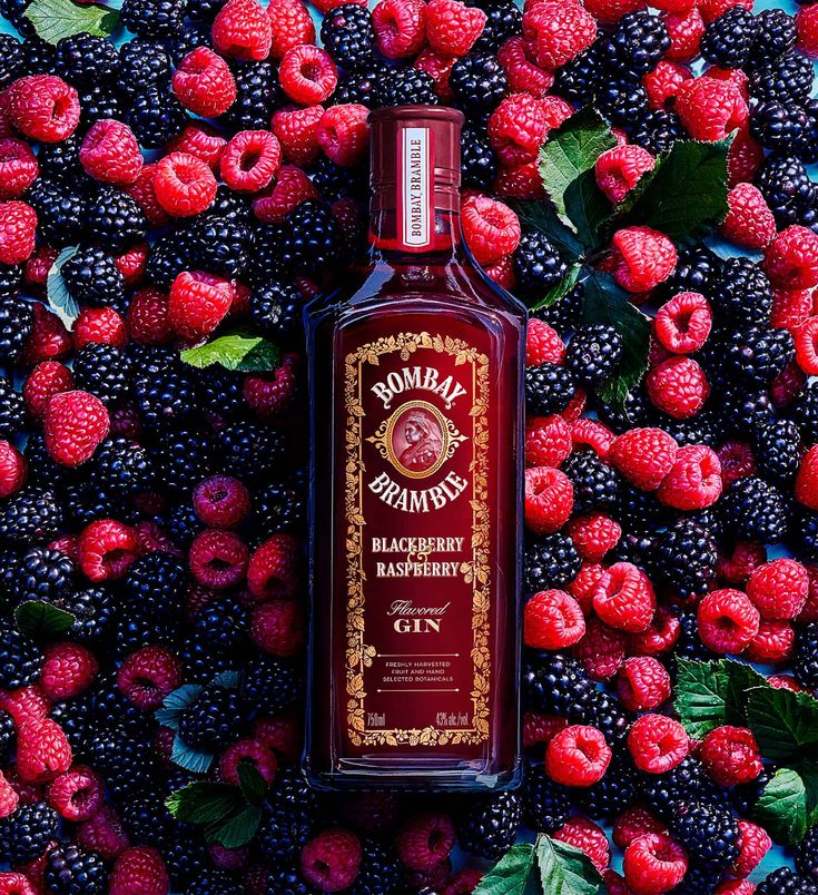 a bottle of liquor surrounded by raspberries and blackberries