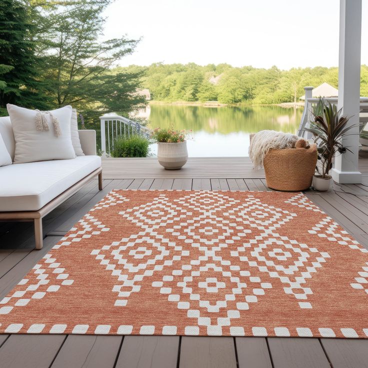 an orange and white rug sitting on top of a wooden deck next to a lake