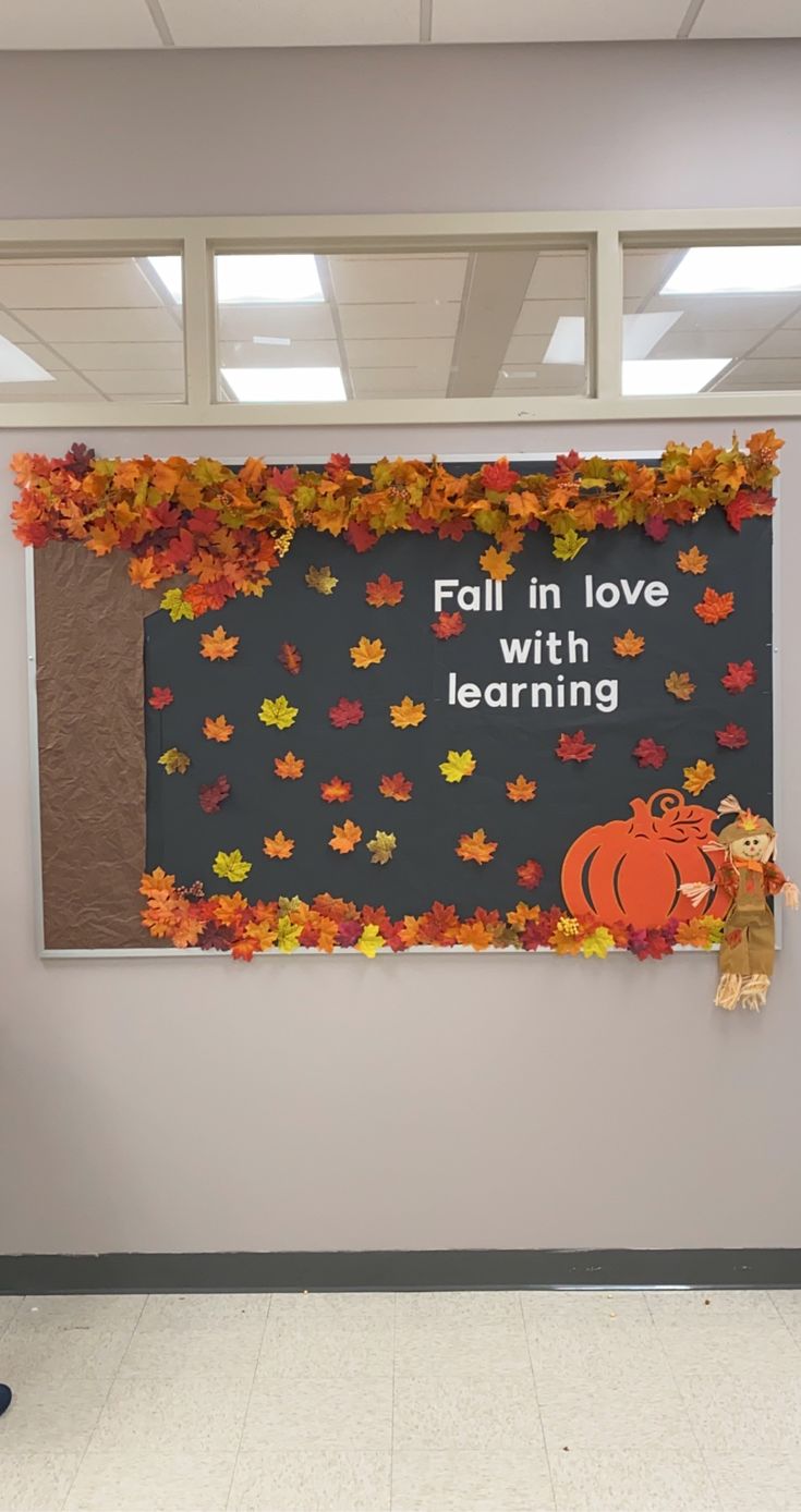 a bulletin board with fall leaves on it and a teddy bear standing in front of it