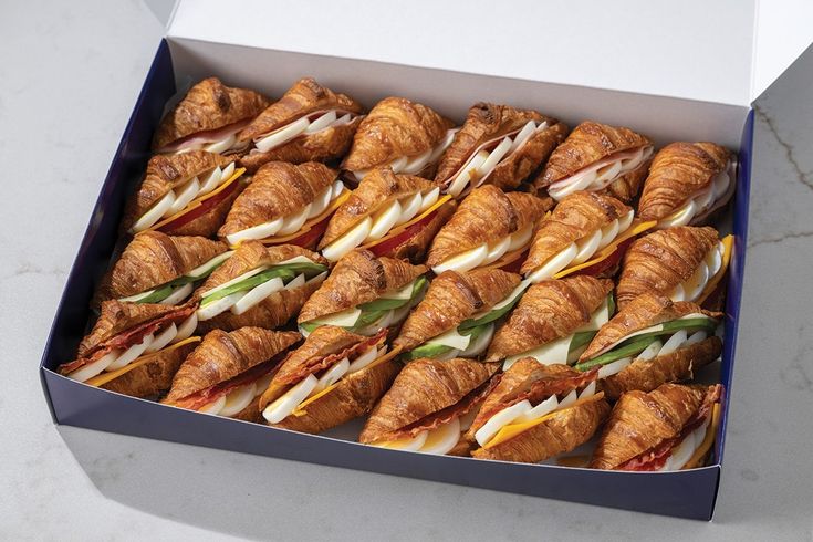 a box filled with croissants covered in cheese and meat sitting on top of a table