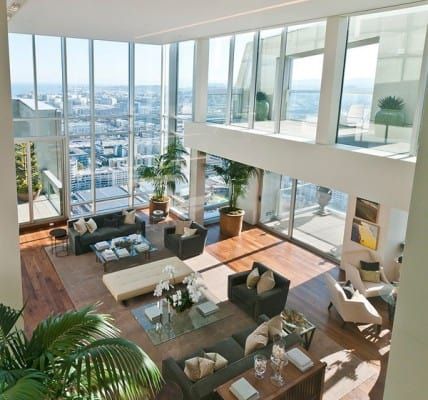 a living room filled with lots of furniture and large windows overlooking the cityscape