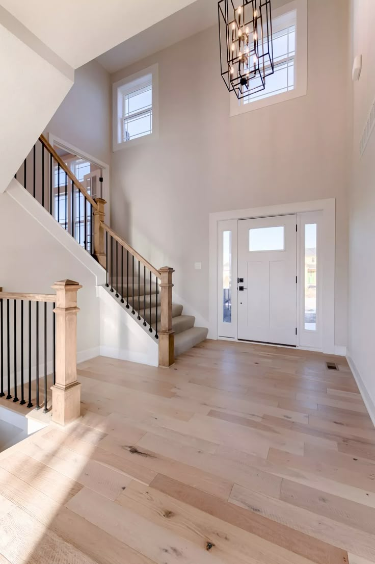 an empty entryway with stairs and chandelier