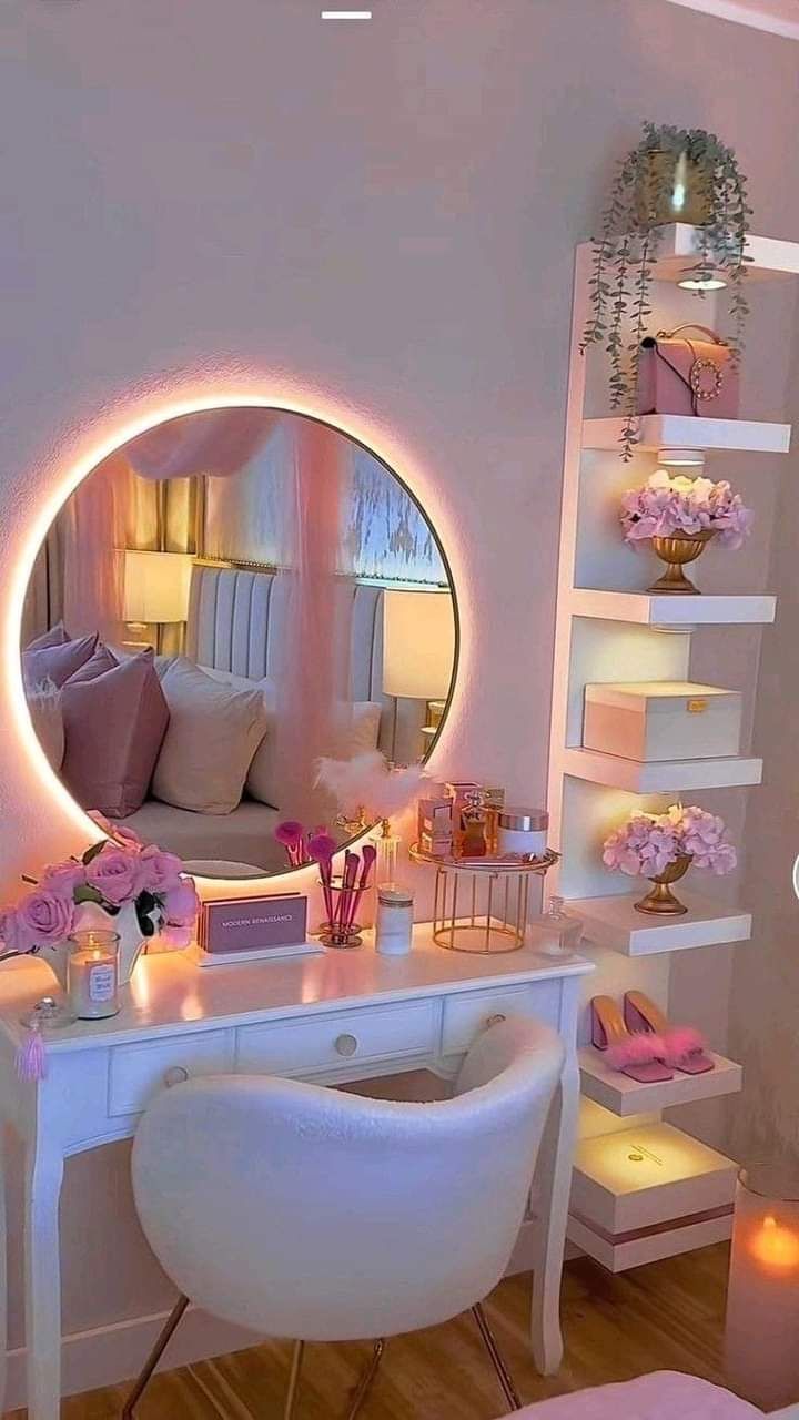 a white desk topped with a mirror next to a chair and a shelf filled with flowers