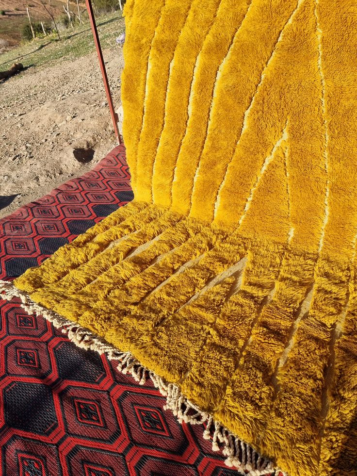 a yellow chair sitting on top of a red and black rug next to a field