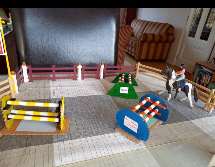 a toy horse and rider in a room with miniature obstacles on the floor next to each other