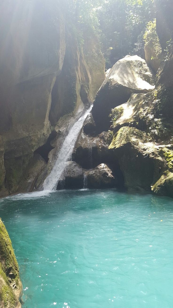 there is a small waterfall in the middle of this blue pool with water running down it