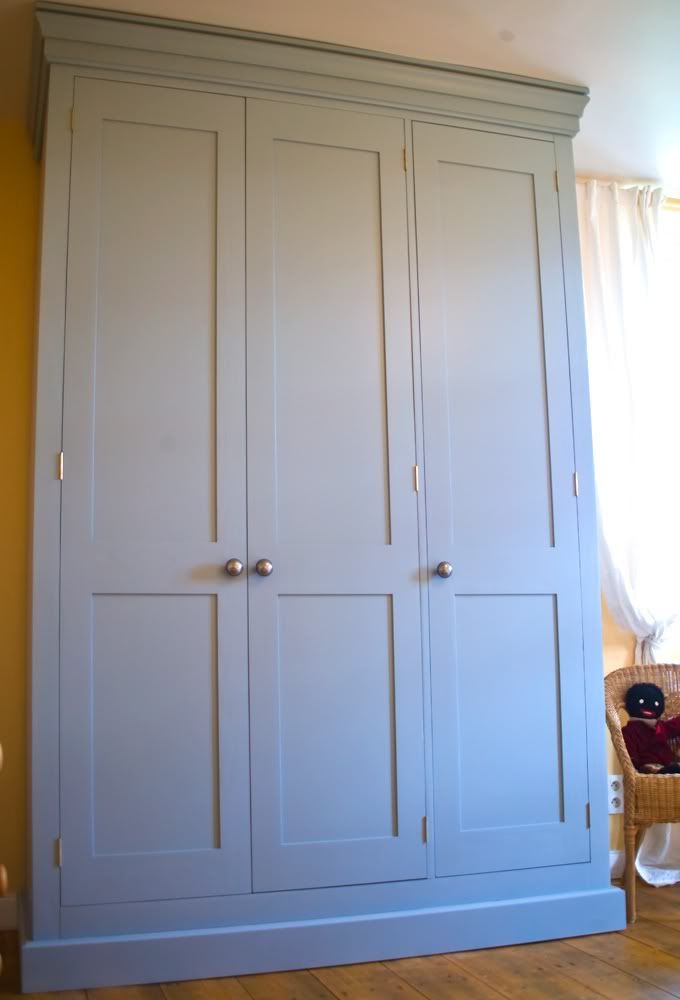 a white armoire in a room with wood floors