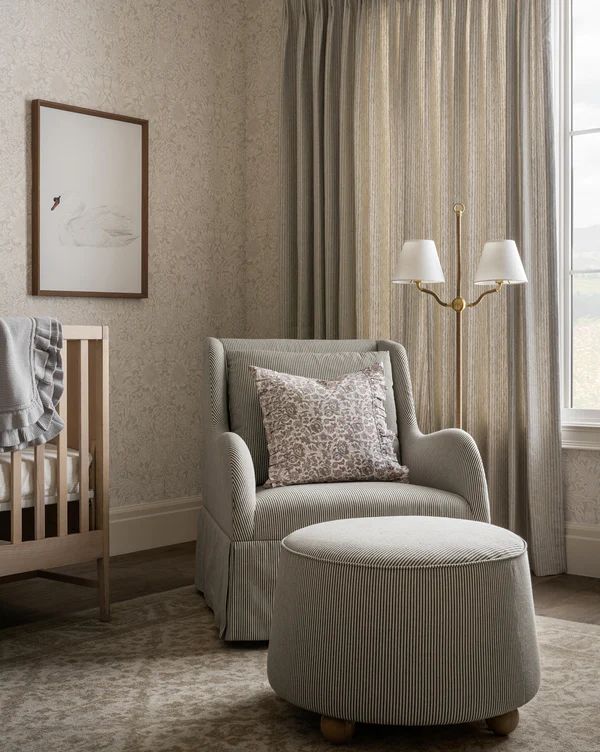 a baby's room with a chair, crib and window