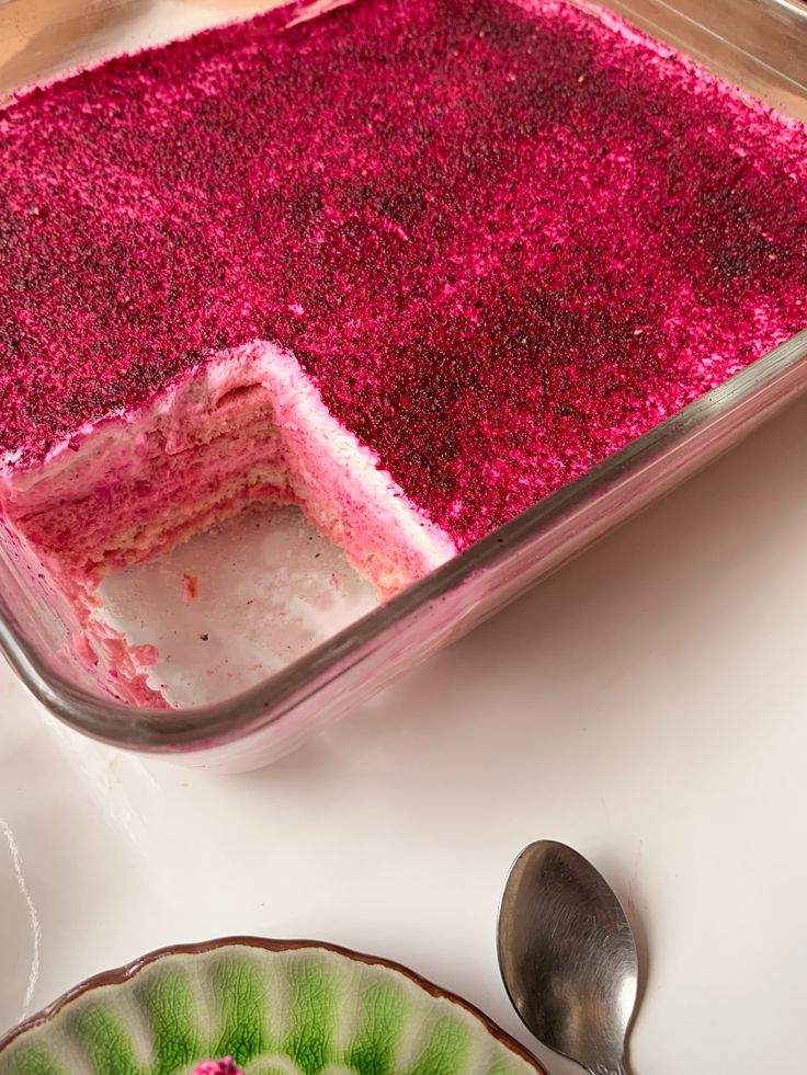 a cake with pink frosting and sprinkles in a pan on a table