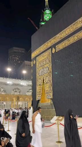 many people are walking around in front of the ka'bah at night time