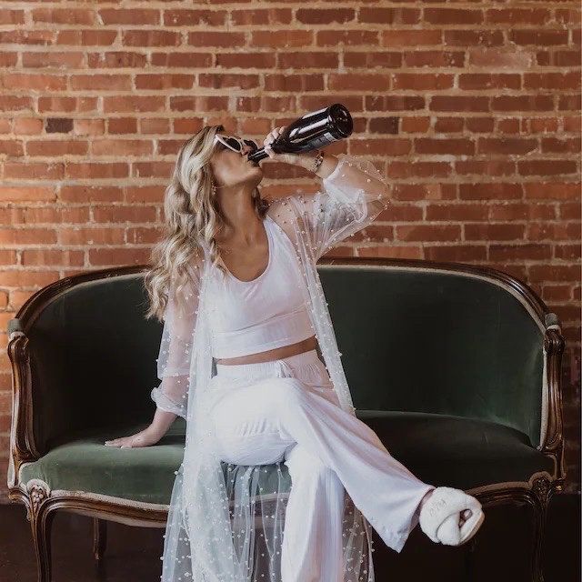 a woman sitting on a couch drinking from a bottle