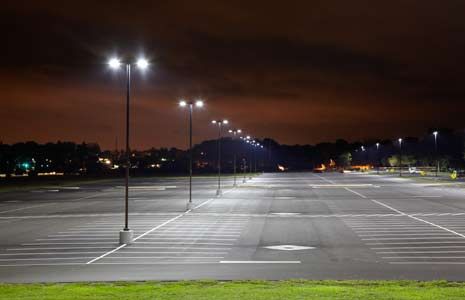 an empty parking lot at night with street lights on the sides and grass in the foreground