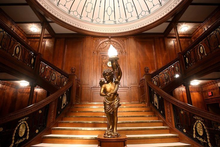 an ornate staircase with a statue on the bottom and a clock above it in a building