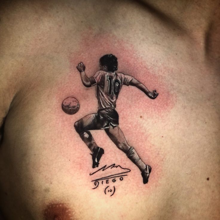 a man with a tattoo on his chest has a soccer ball in front of him