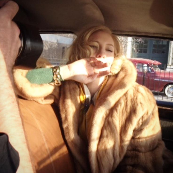 a woman sitting in the back seat of a car with her hand on her lips