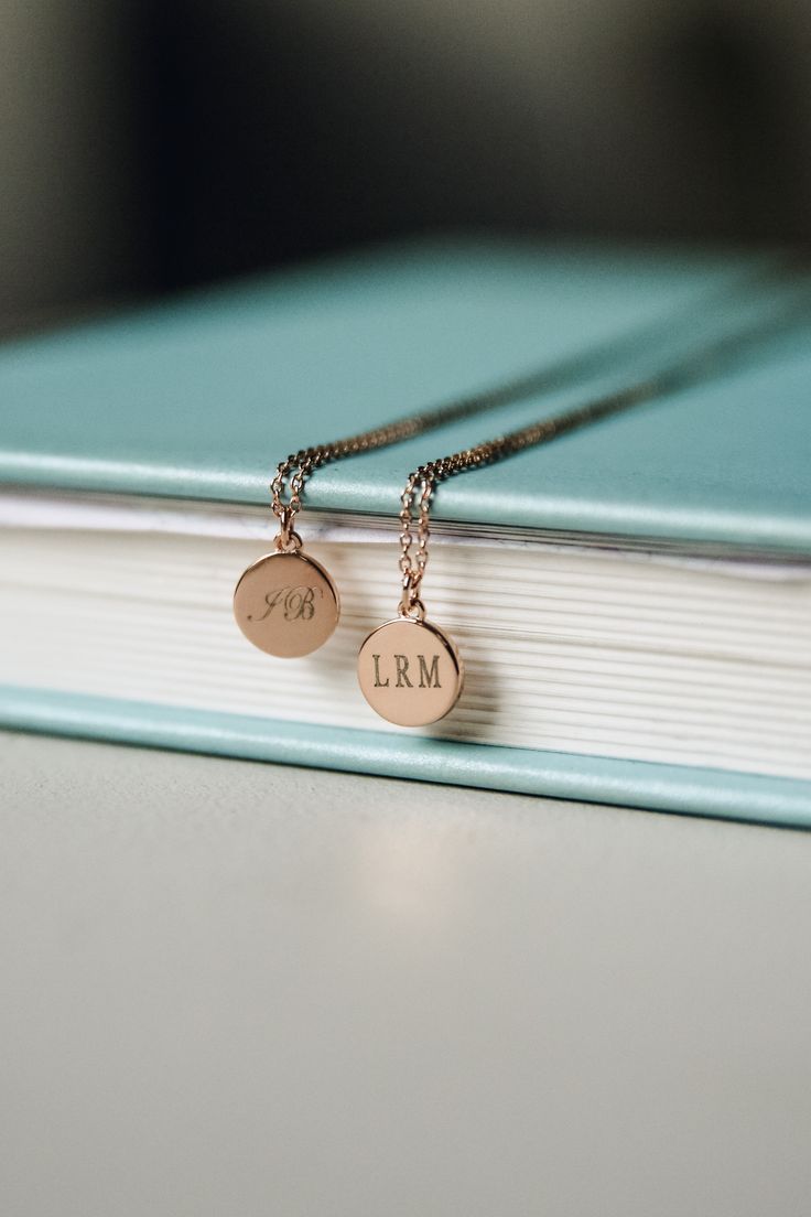 two personalized necklaces sitting on top of a book with the word i am written on it