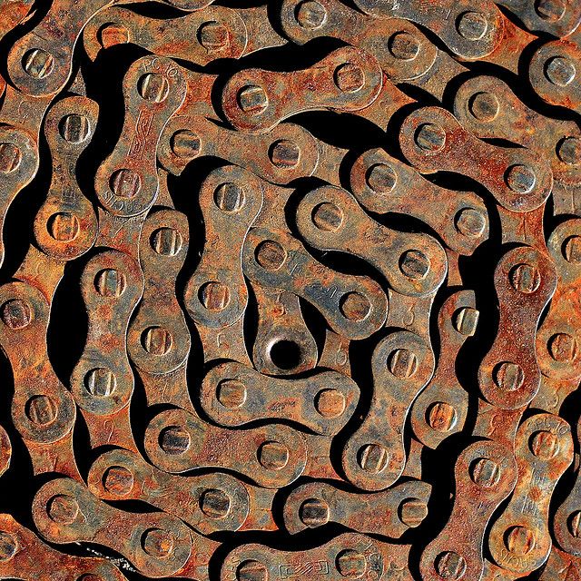 an old rusted bike chain with holes in the middle and some circles on it