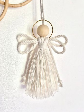 an angel ornament hanging on a wall next to two circular rings and a wooden bead