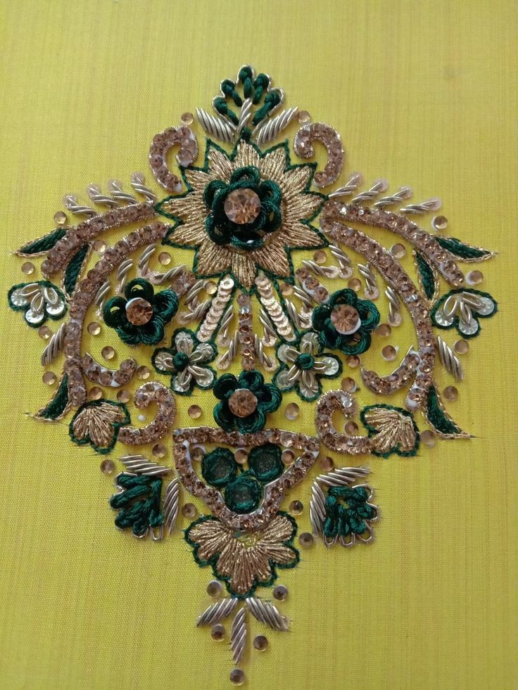 a green and gold brooch on a yellow background