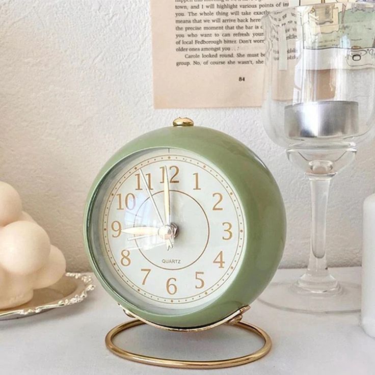 an alarm clock sitting on top of a table next to a wine glass and egg