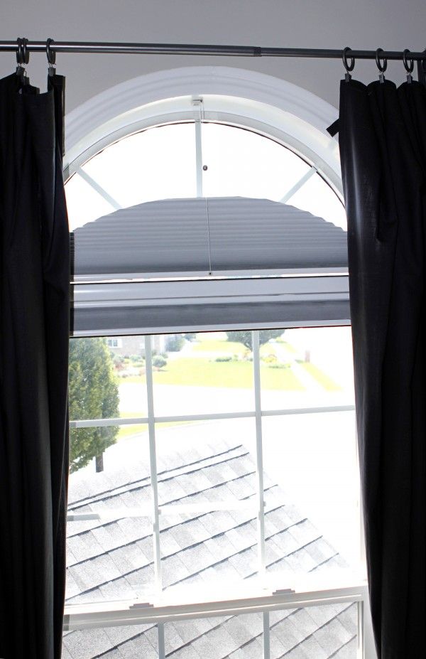 an open window with black curtains in front of it and a view of the roof