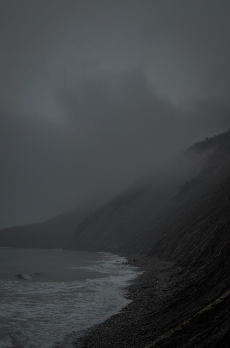 the beach is covered in dark, foggy weather