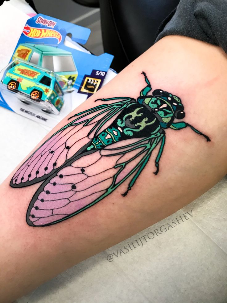 a colorful insect tattoo on the left arm and leg, next to a toy truck