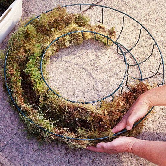 someone is making a wreath out of twigs and grass on the ground with their hands