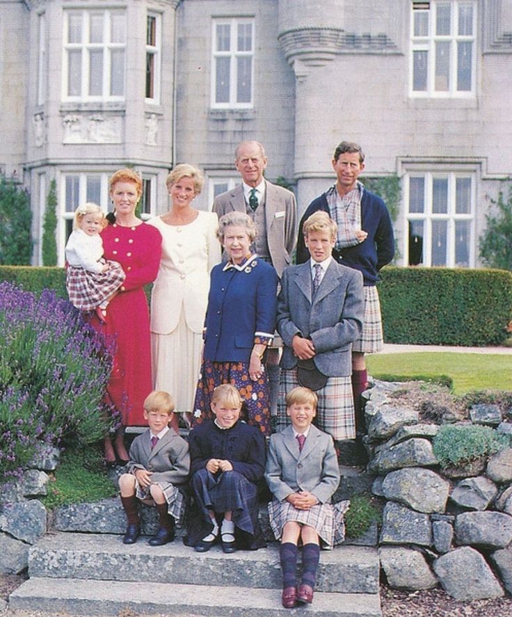 a group of people standing on steps in front of a building with bushes and flowers