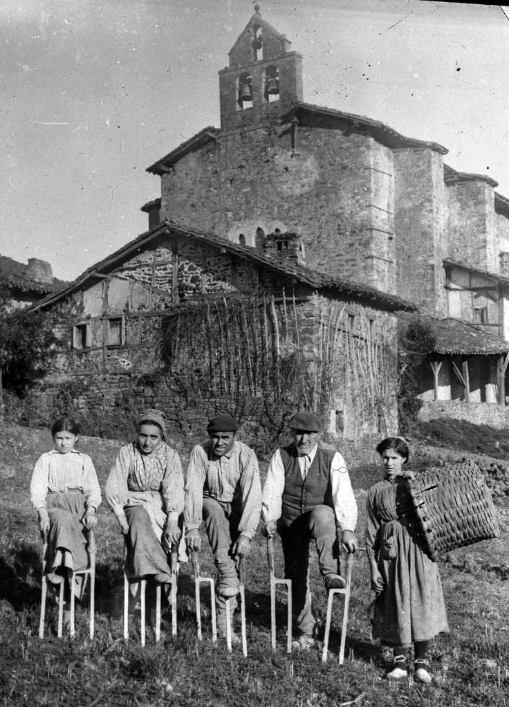 an old black and white photo of people sitting on chairs in front of a building