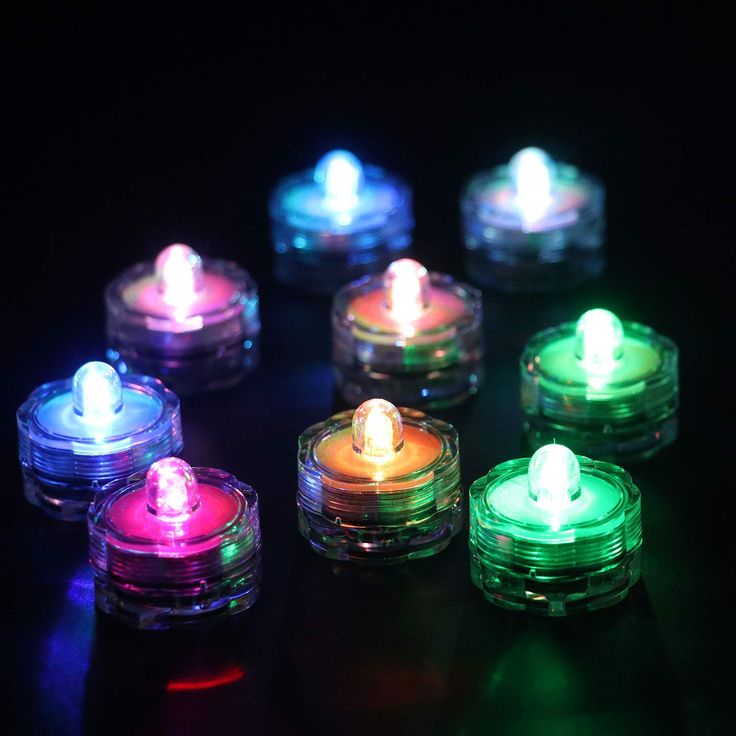 several lit candles sitting on top of each other in different colors and sizes, all glowing brightly