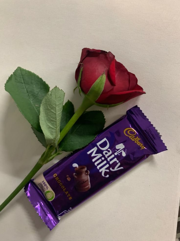 a single rose and chocolate bar on a table