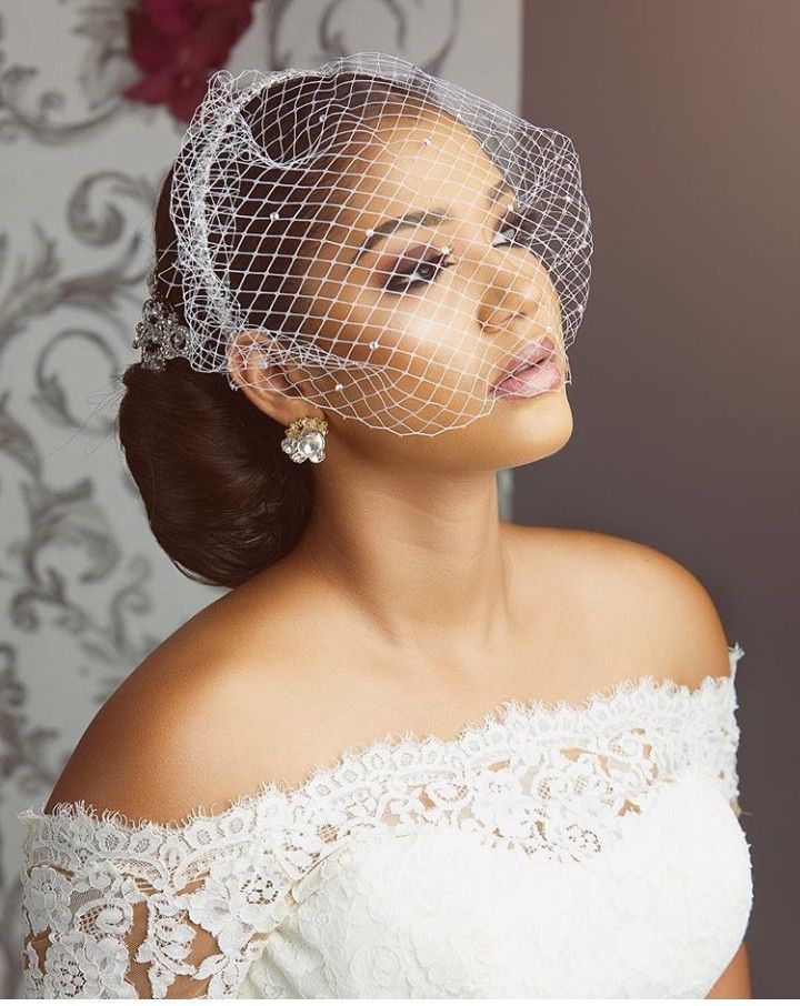 a woman with a veil on her head wearing a white dress and wedding hairpiece