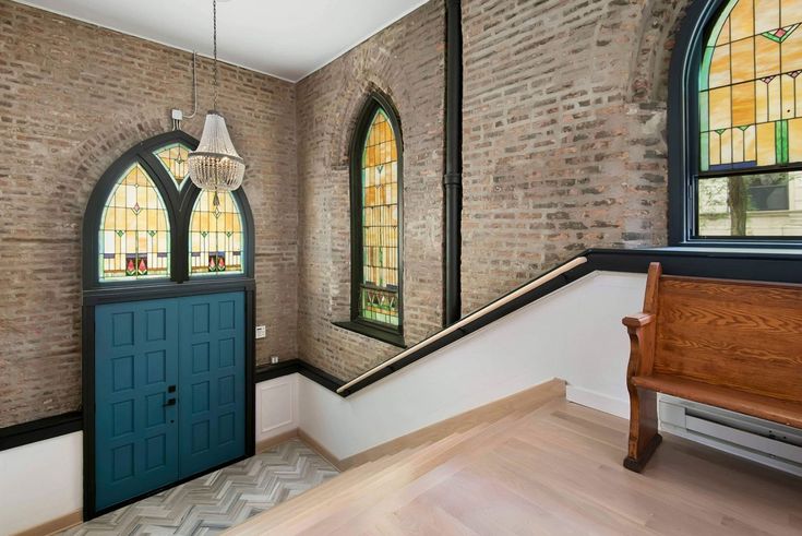 an entryway with stained glass windows and a wooden bench in the foreground, next to a brick wall