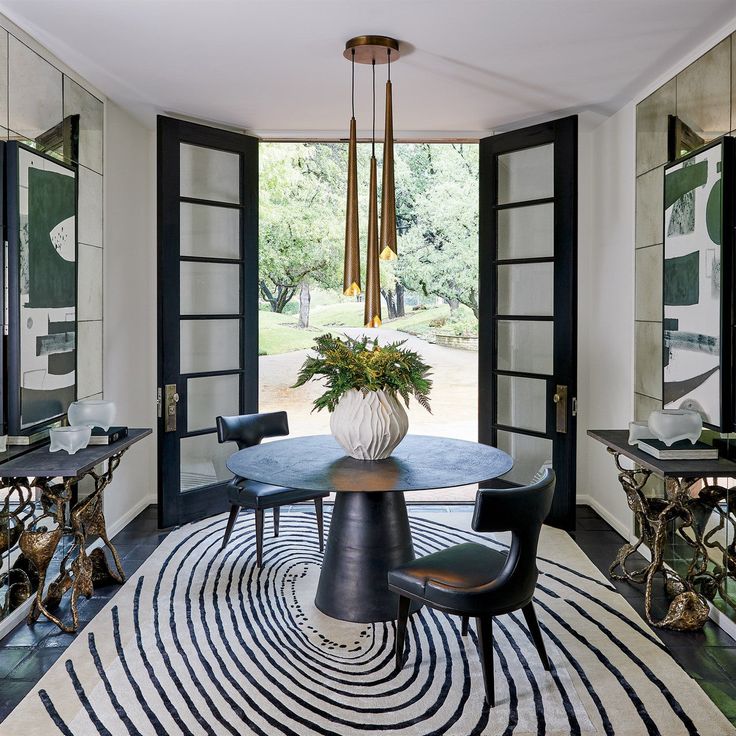 an elegant dining room with black and white rugs, gold chandelier, round table and chairs